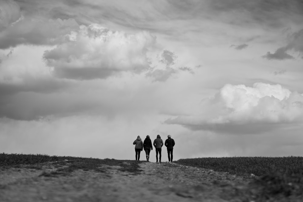 3 personnes debout sur un sol enneigé sous un ciel nuageux pendant la journée