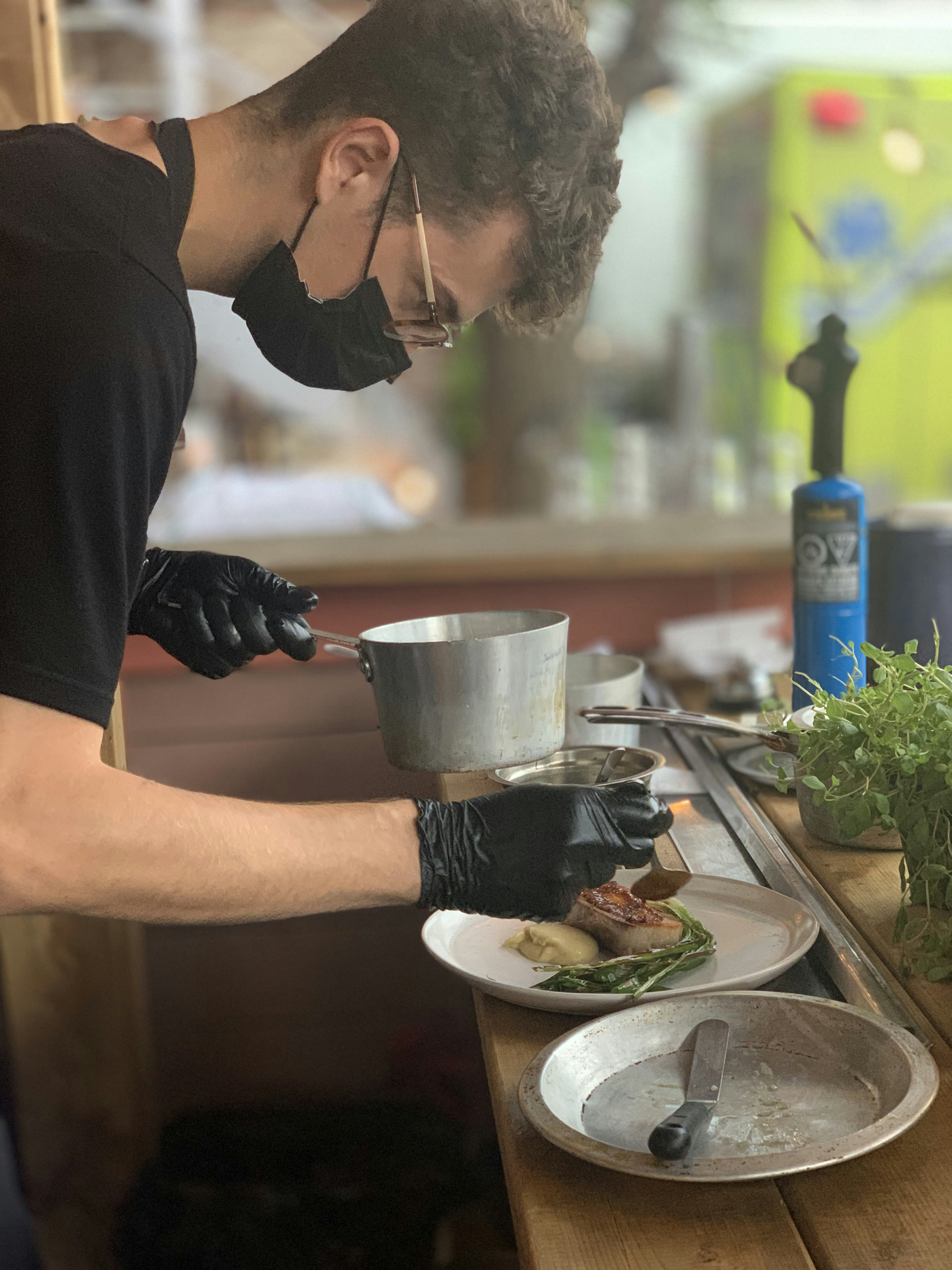 Mann im schwarzen Langarmhemd, der Wasser auf Edelstahlbecher gießt