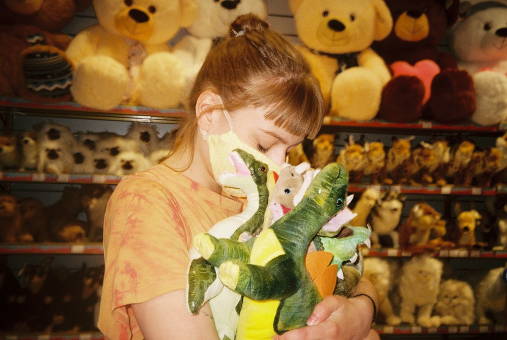 girl in pink shirt holding green frog plush toy