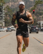 man in black tank top running on road during daytime