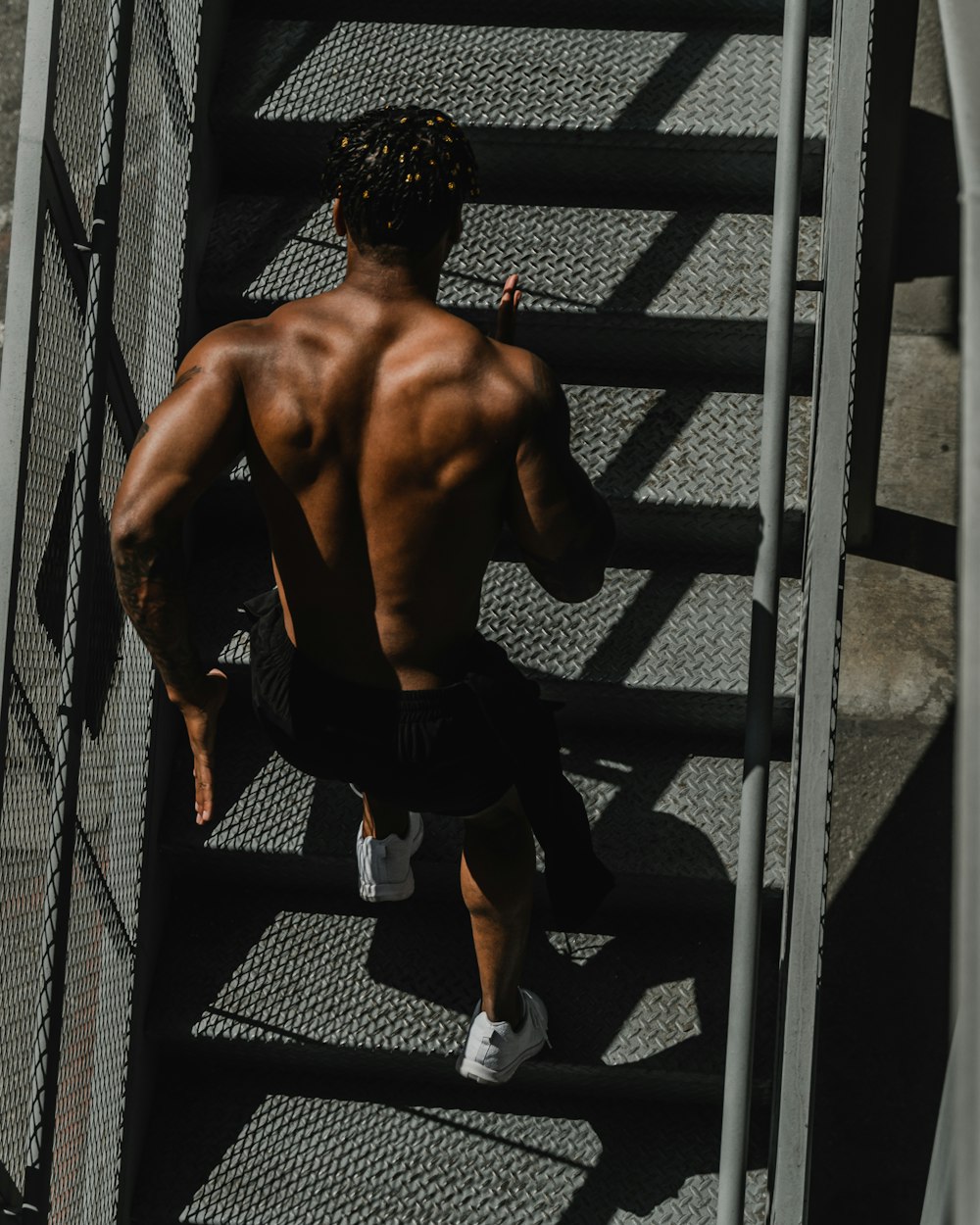 man in black shorts sitting on black metal fence