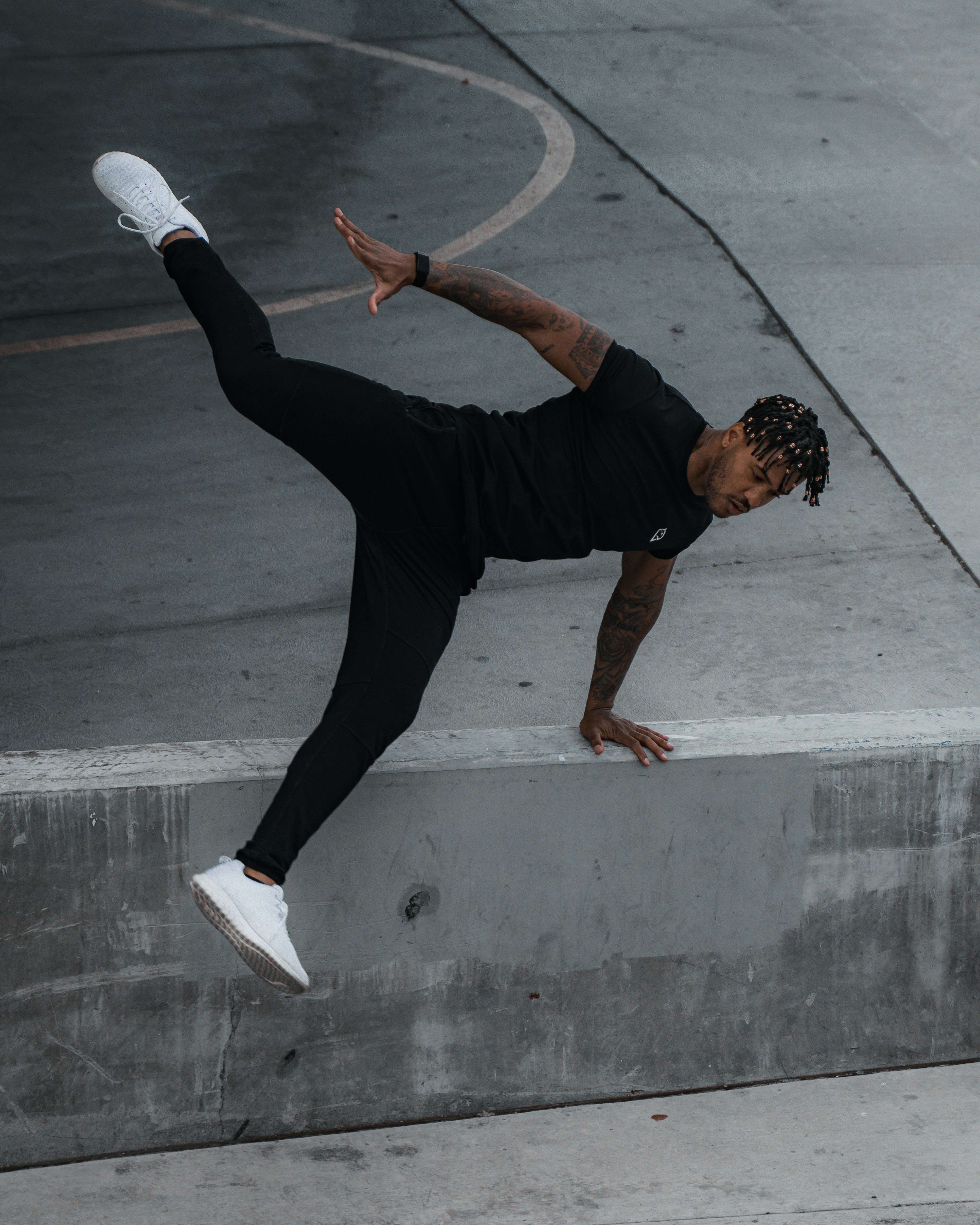 man in black pants and white socks jumping on gray concrete floor during daytime
