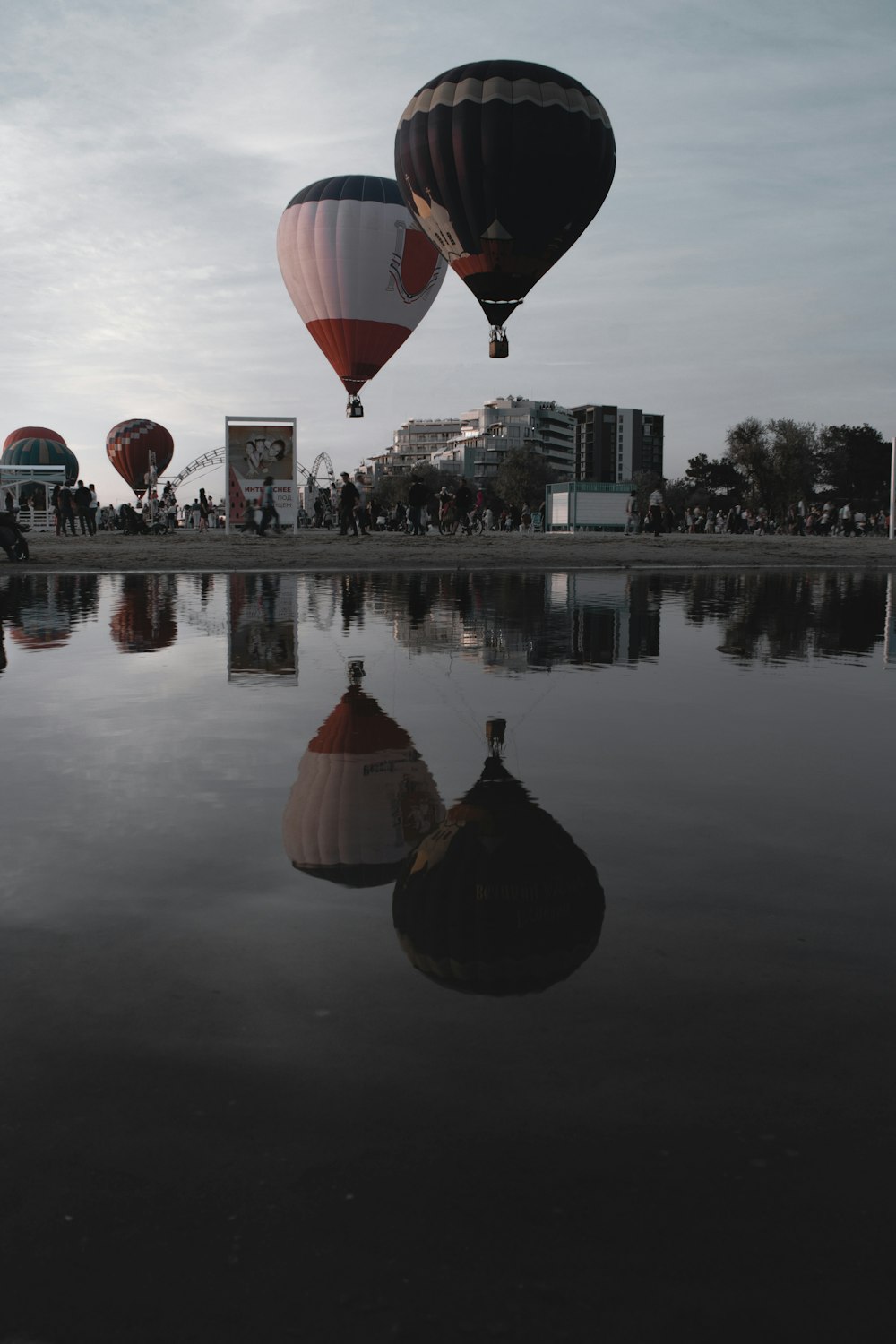 Eine Gruppe von Heißluftballons fliegt über einen See