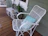 A cozy porch scene featuring a white farmhouse side table with a potted plant and a cup of coffee.