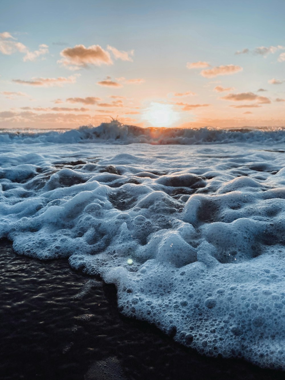 ocean waves crashing on shore during sunset