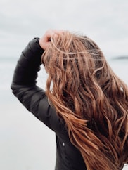 woman in black leather jacket covering her face with her hair