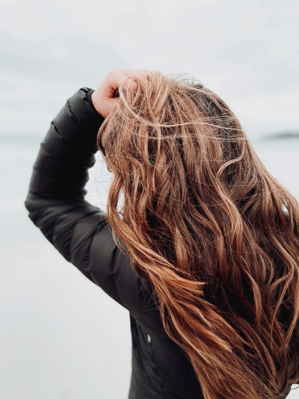 woman in black leather jacket covering her face with her hair