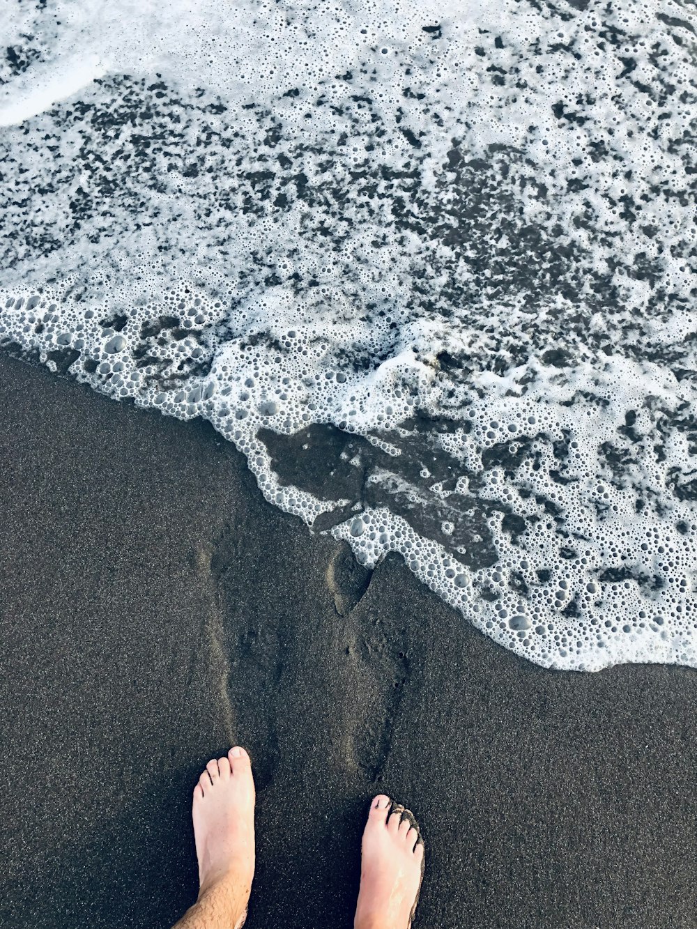 Persona in piedi sulla riva della spiaggia durante il giorno