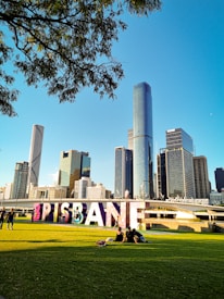 people sitting on green grass field near high rise buildings during daytime