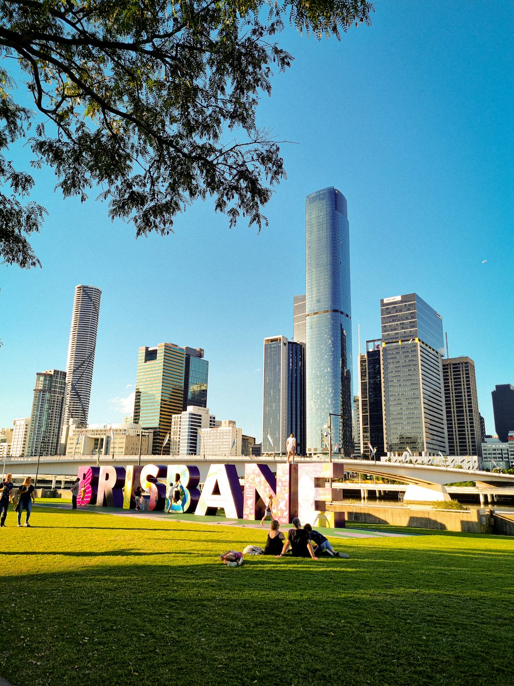 people sitting on green grass field near high rise buildings during daytime