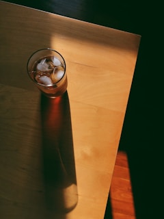 A chilled glass of iced tea catching afternoon light, placed beside the rocking chair on a rustic wooden porch.