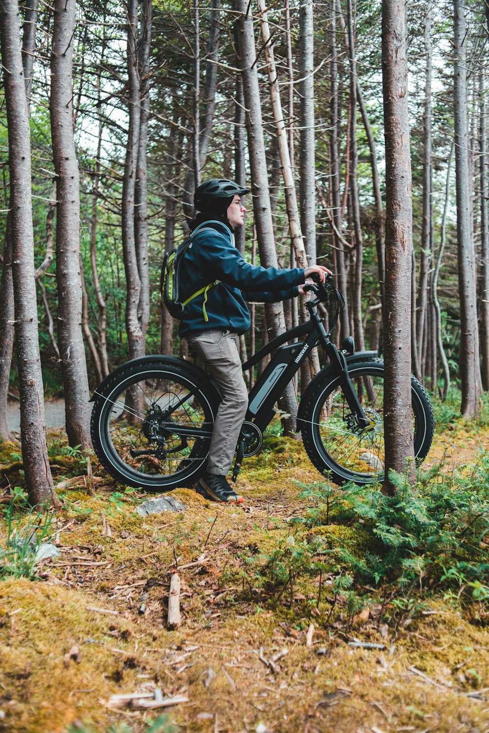 Hombre con chaqueta negra montando bicicleta de montaña negra en el bosque durante el día