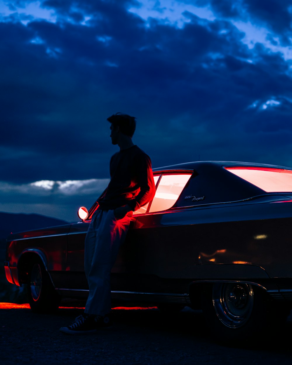 man in black shirt and pants sitting on red car