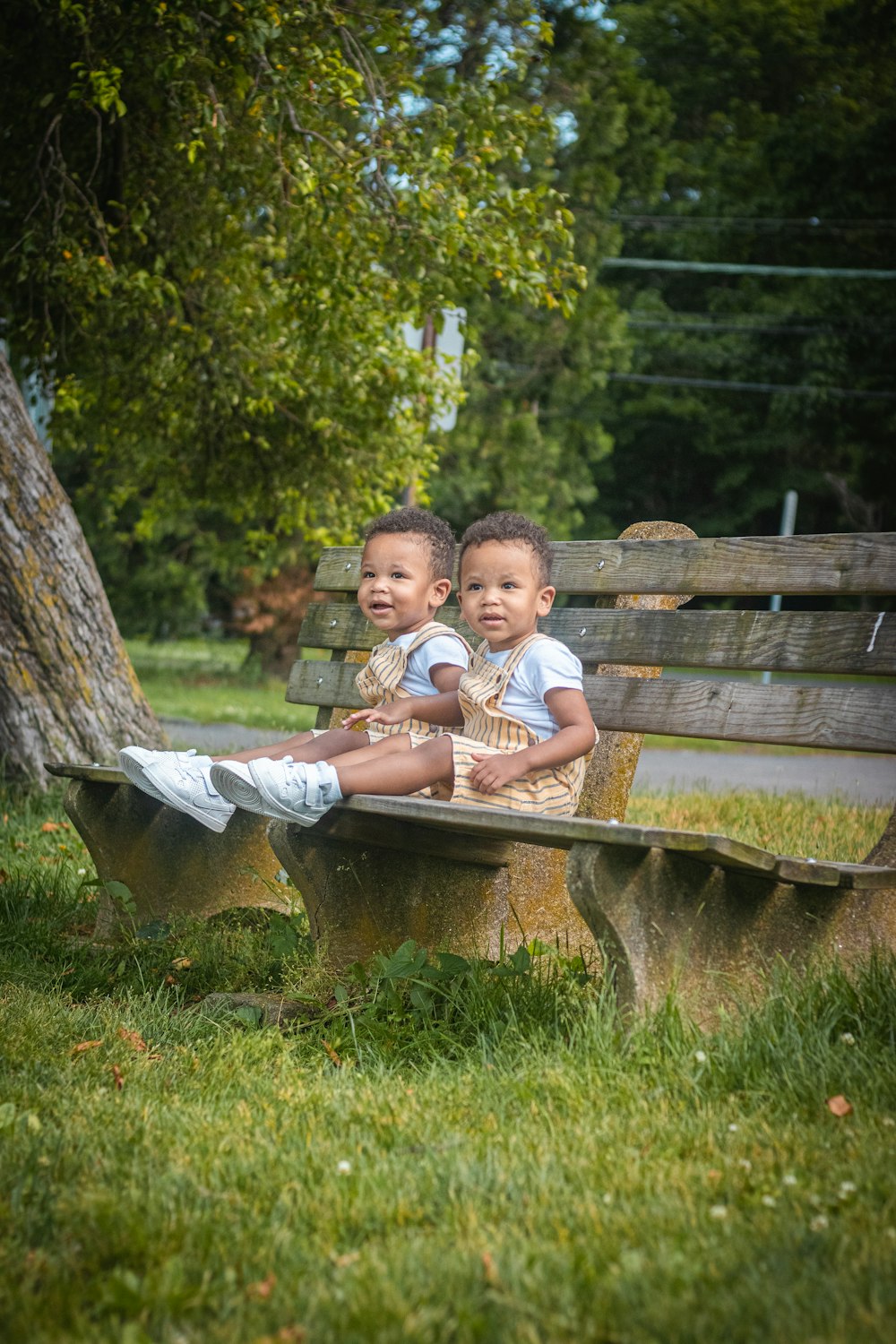 duas crianças pequenas sentadas em um banco de parque
