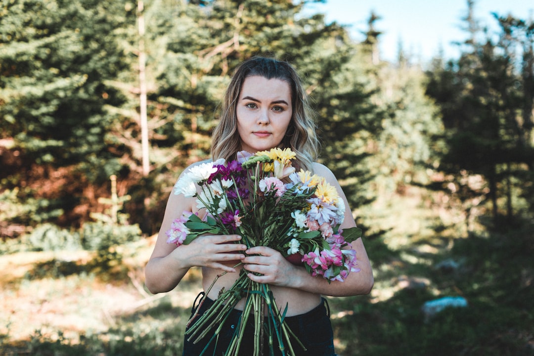 woman in black and pink floral dress holding bouquet of flowers