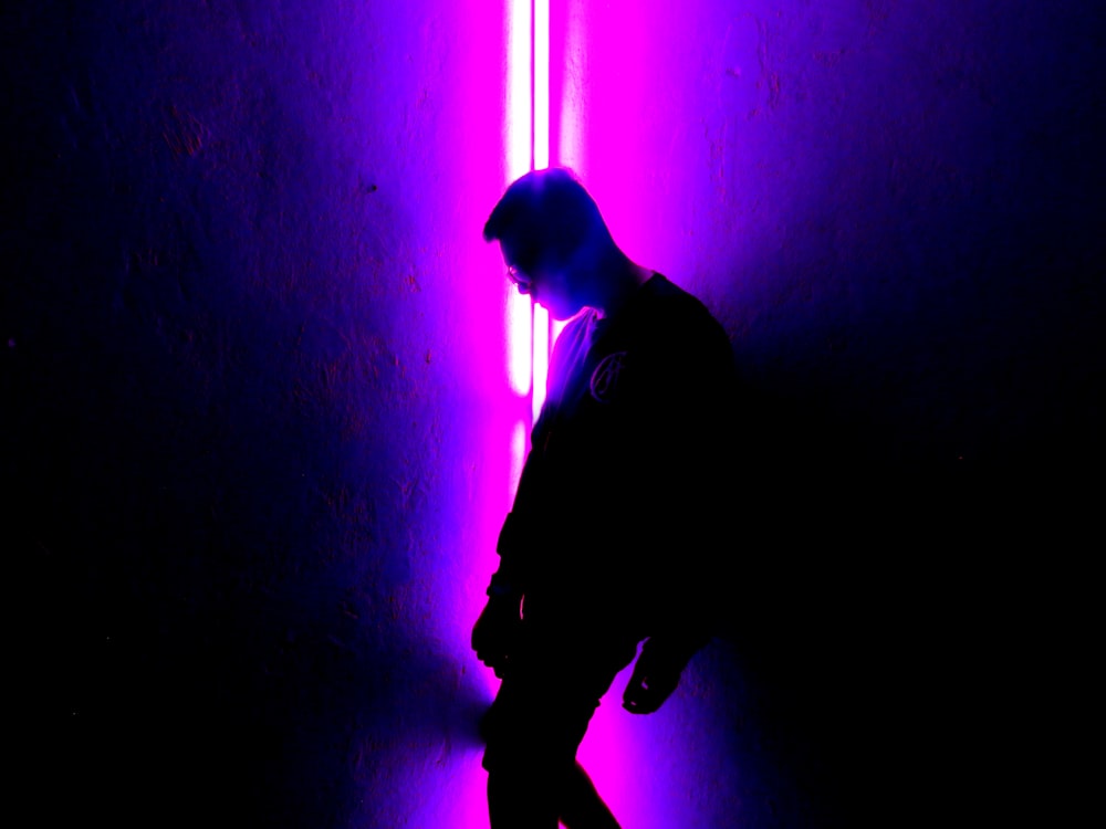 Un hombre parado frente a una luz púrpura