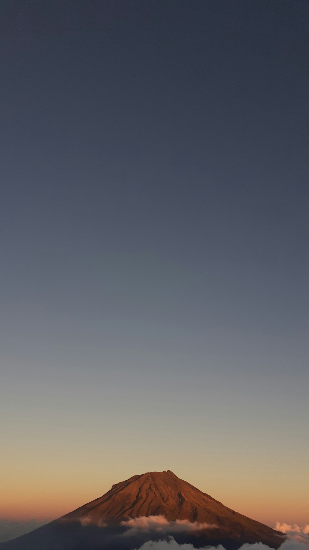 a view of the top of a mountain with clouds below