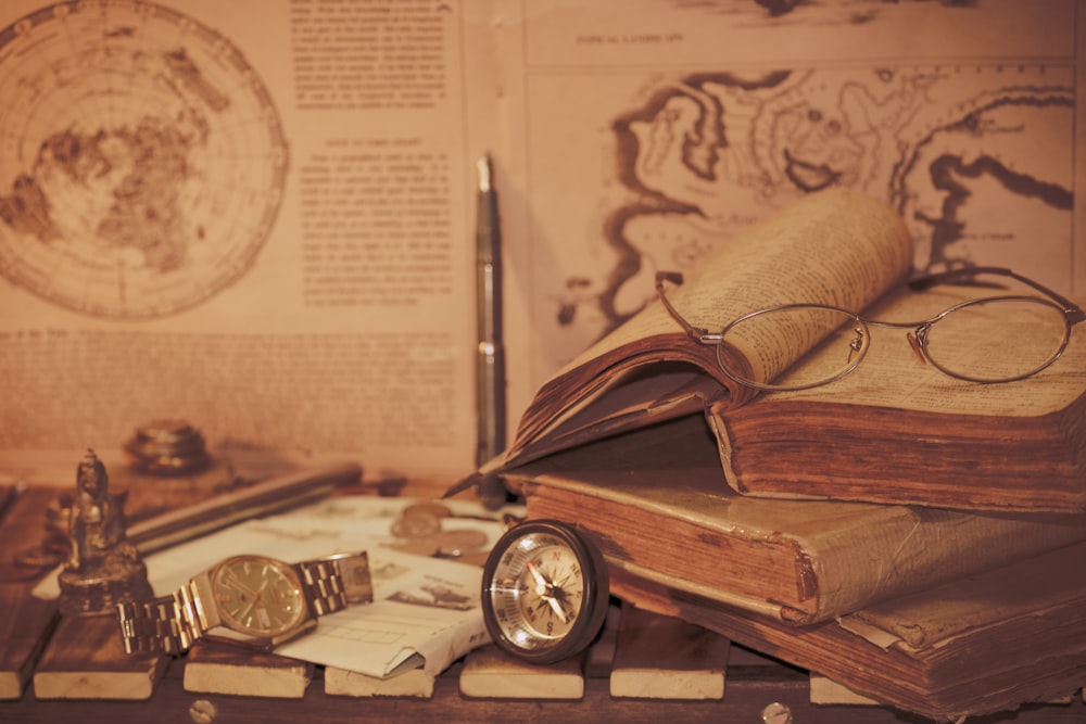 a stack of books and a watch on a table