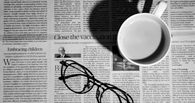 a cup of coffee and a pair of glasses on a newspaper