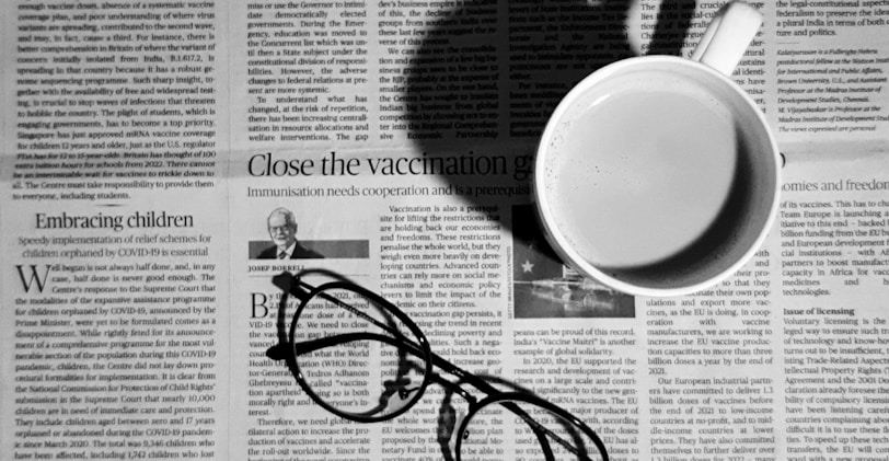 a cup of coffee and a pair of glasses on a newspaper