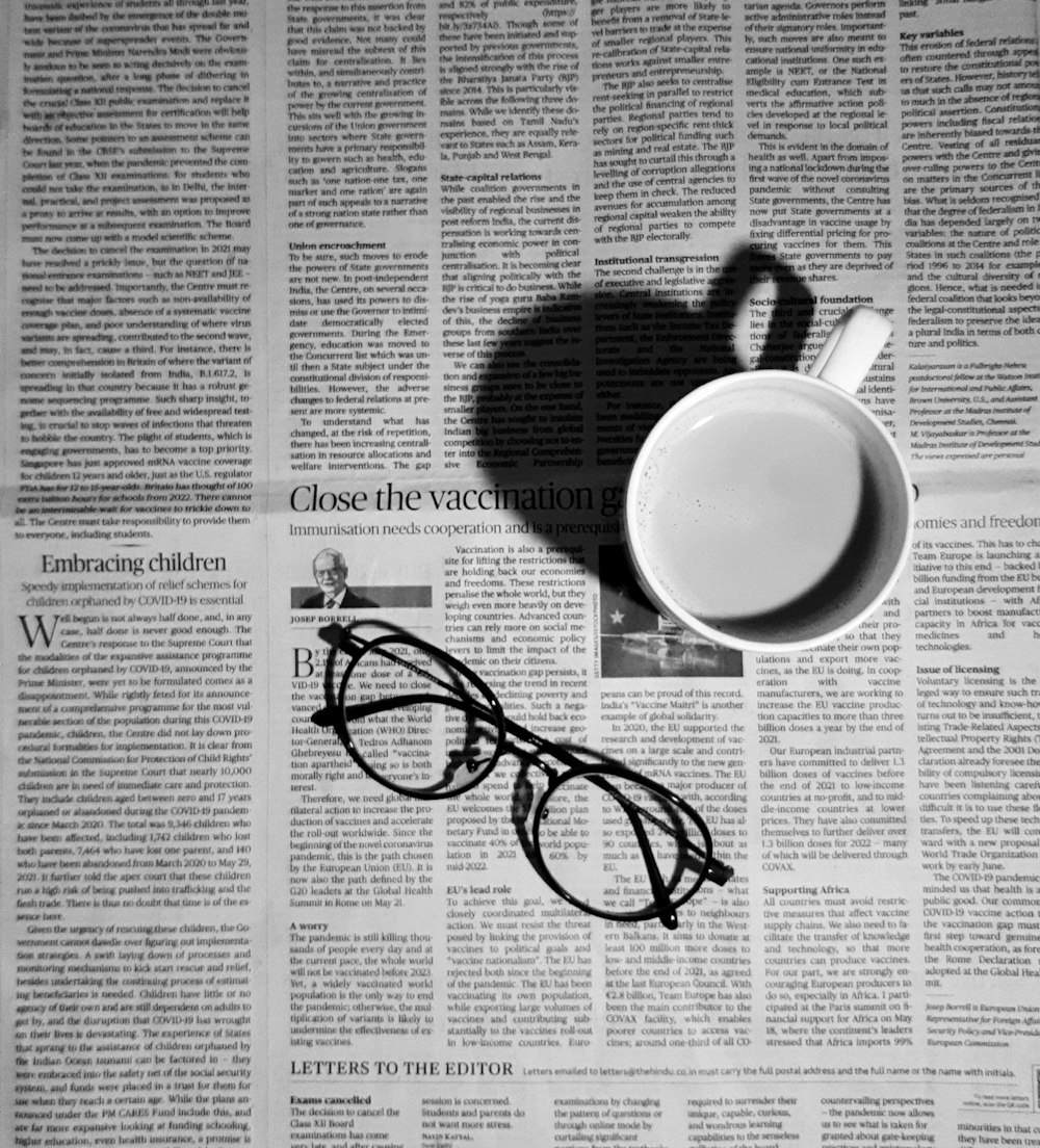 a cup of coffee and a pair of glasses on a newspaper