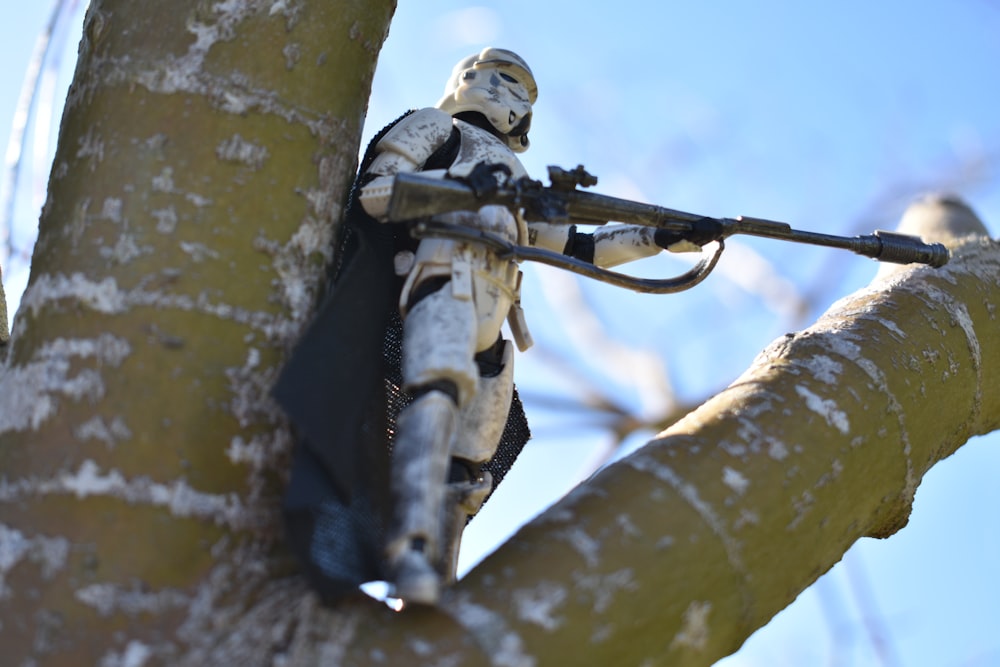 a star wars action figure holding a rifle on a tree