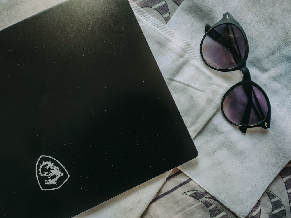 a laptop computer sitting on top of a bed next to a pair of sunglasses