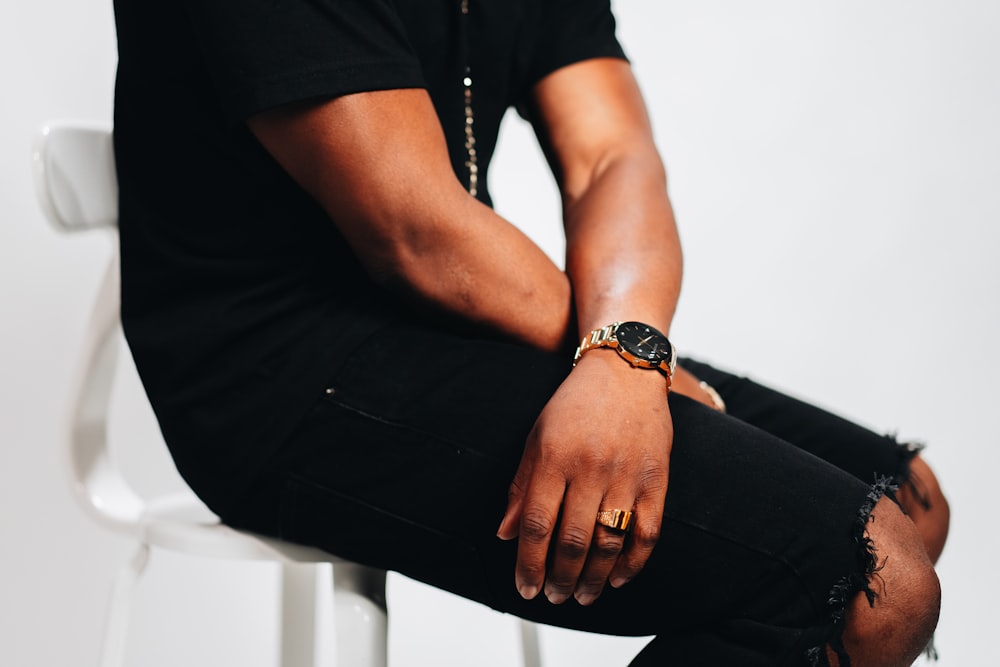 man in black shirt and black pants wearing gold watch