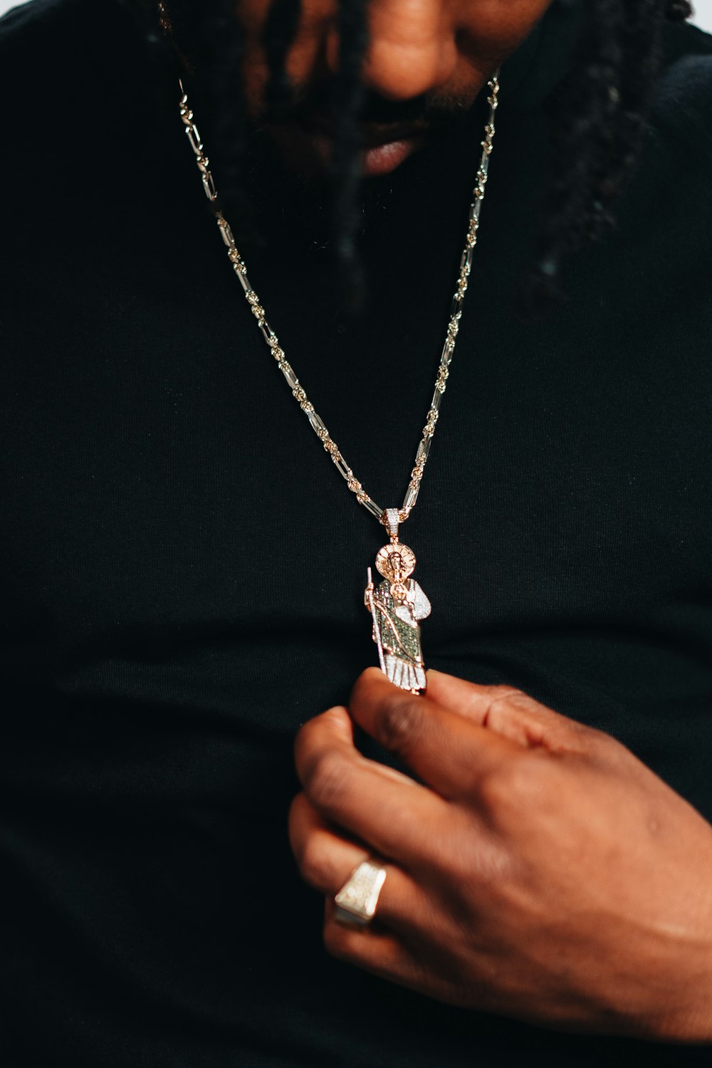 a man wearing a black shirt holding a necklace