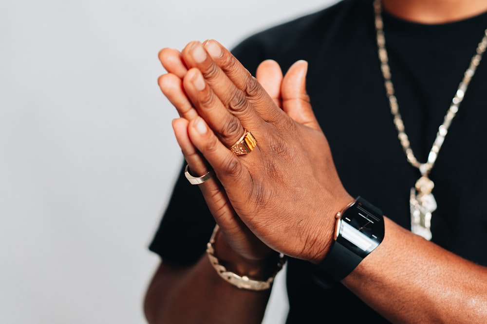 a man in a black shirt is holding his hands together