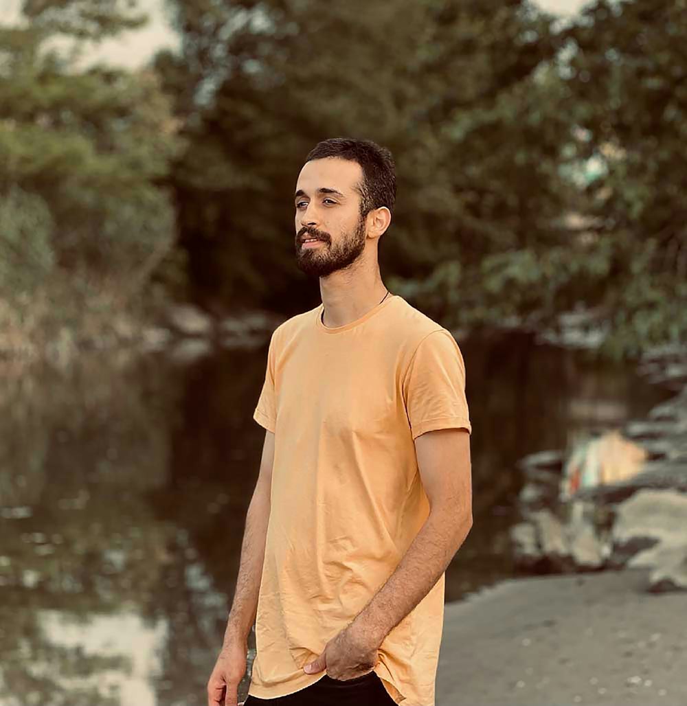 a man standing on a beach next to a body of water