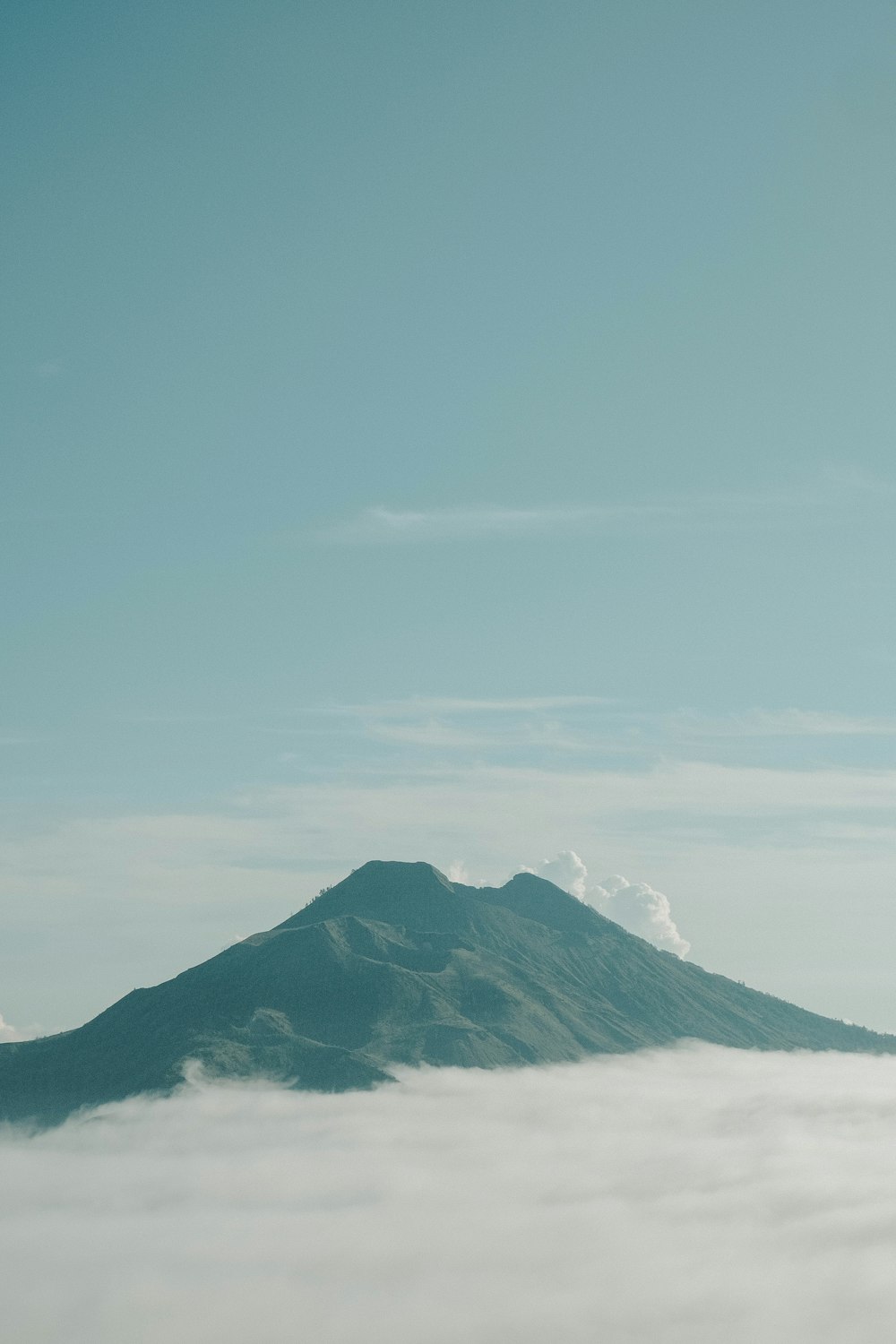 a mountain in the middle of a cloud filled sky