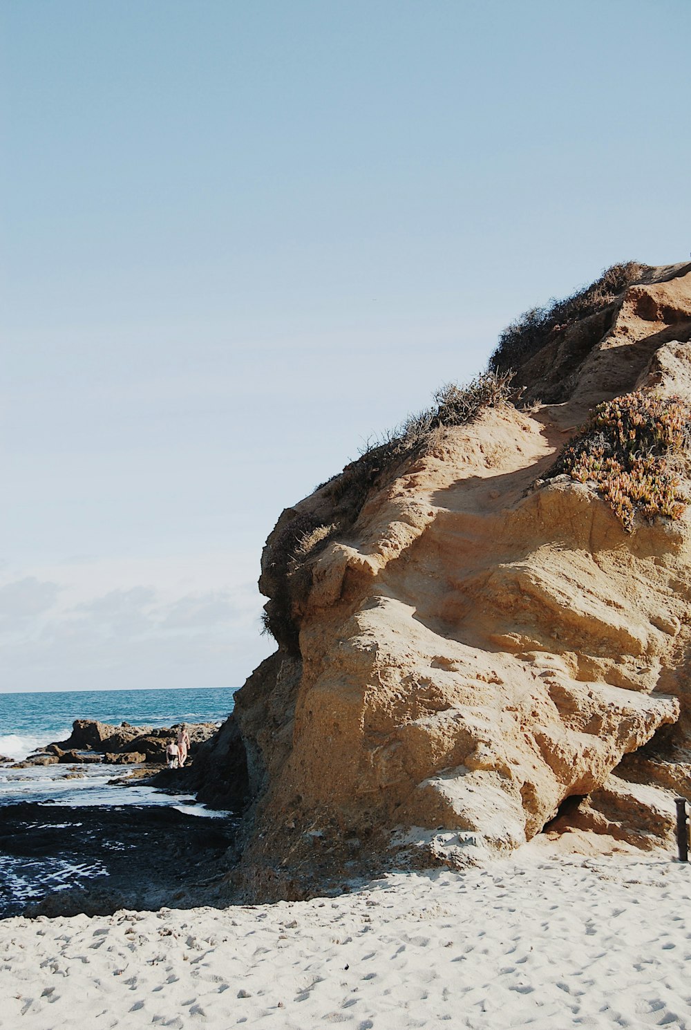 a person standing on a beach next to a large rock