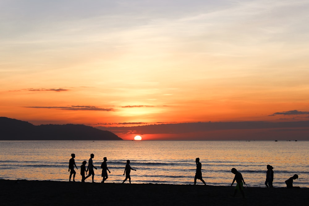 Un groupe de personnes marchant le long d’une plage au coucher du soleil