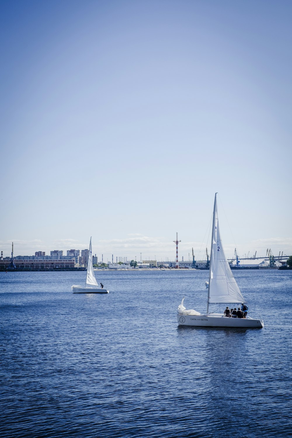 two sailboats in the water with a city in the background