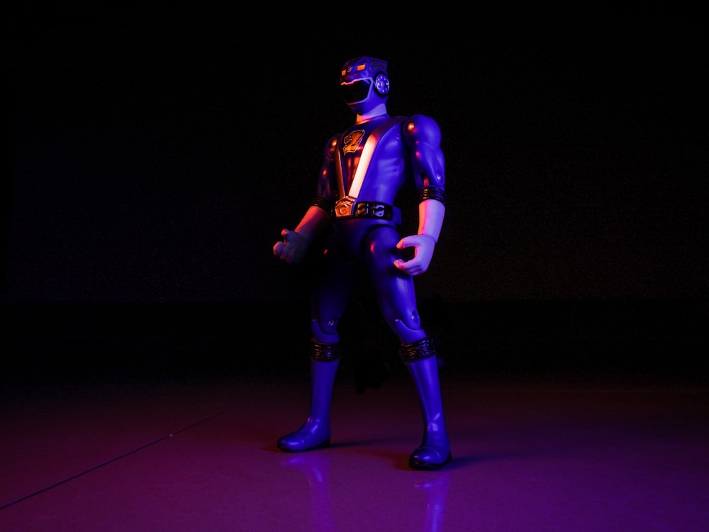 a man in a purple and black costume standing in a dark room