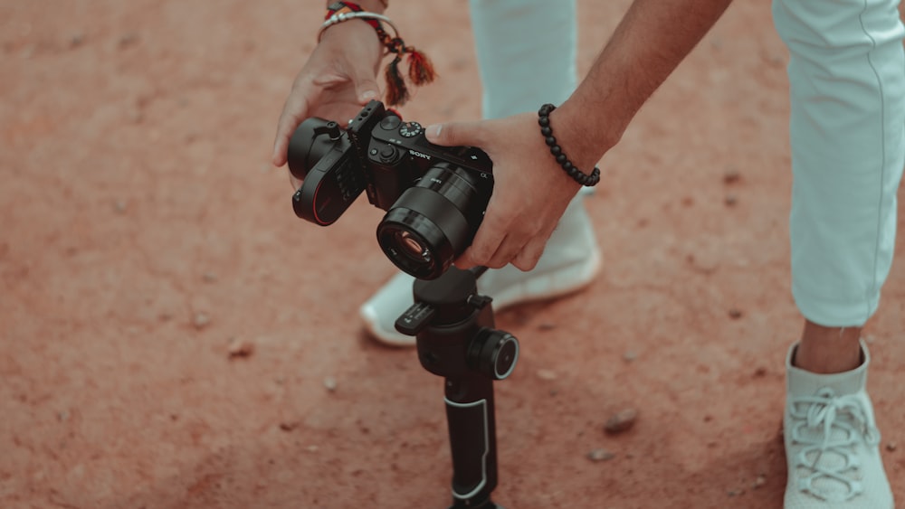 a person holding a camera on top of a tripod