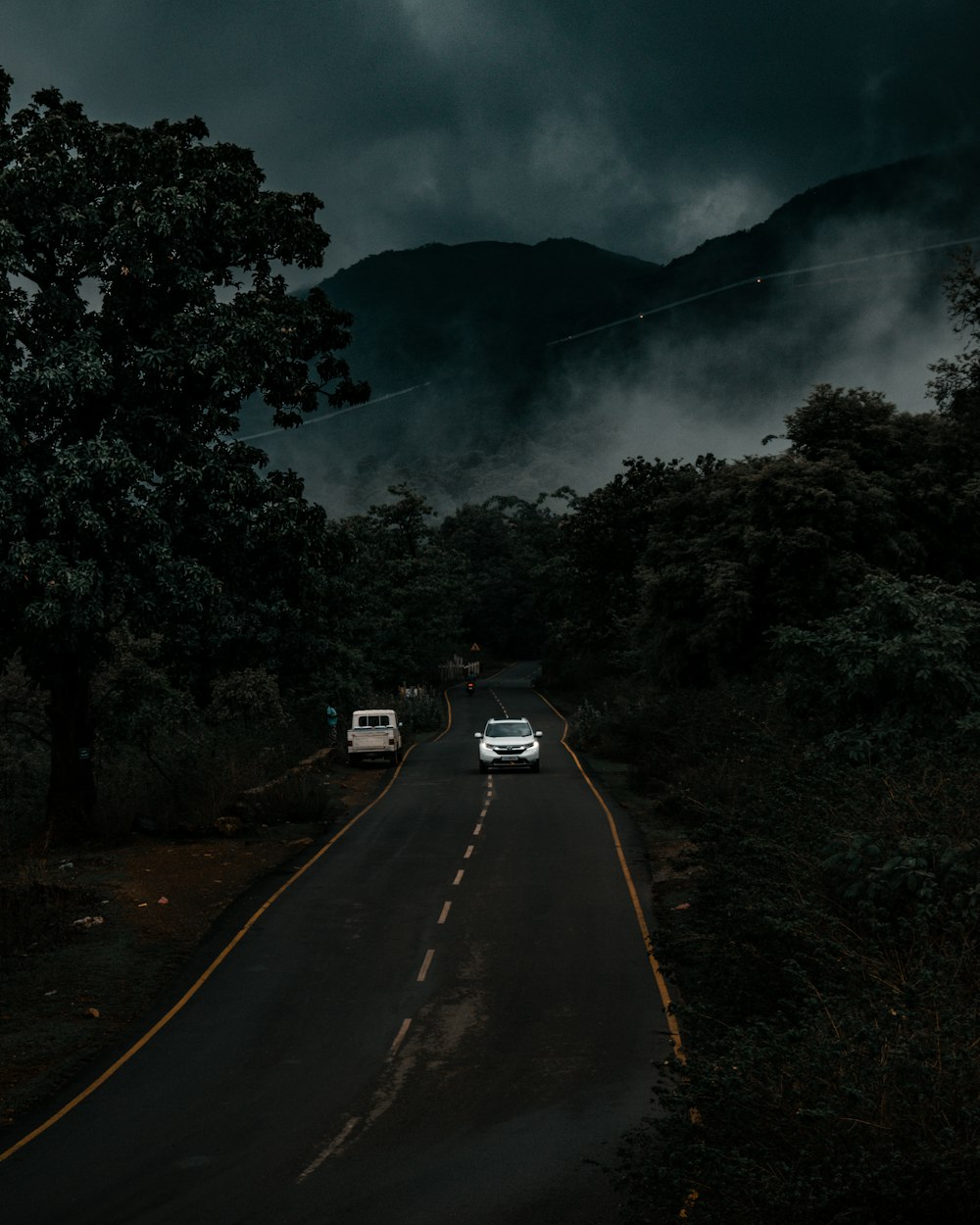 Un paio di auto che guidano lungo una strada sotto un cielo nuvoloso