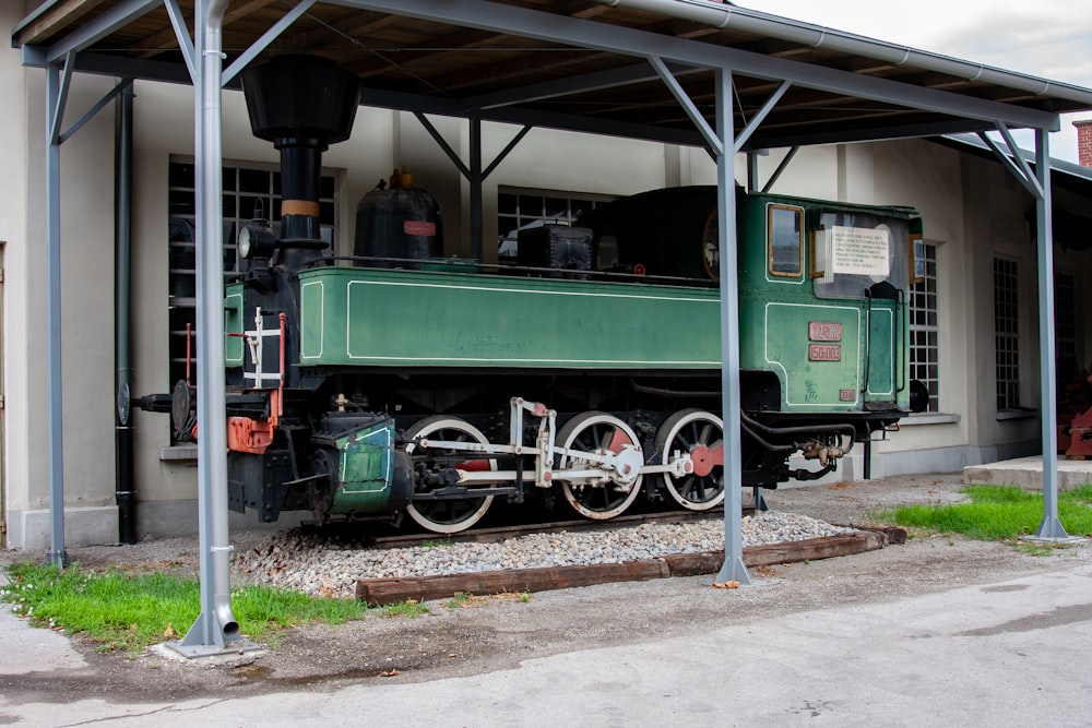 a green train engine sitting in front of a building
