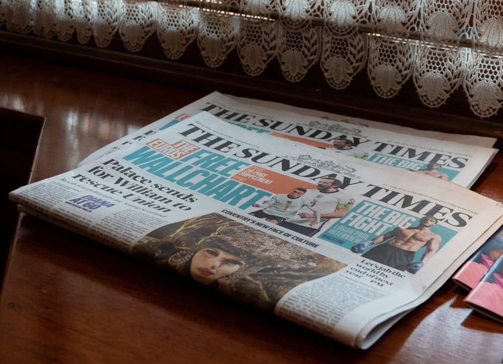 a bunch of newspapers sitting on top of a wooden table