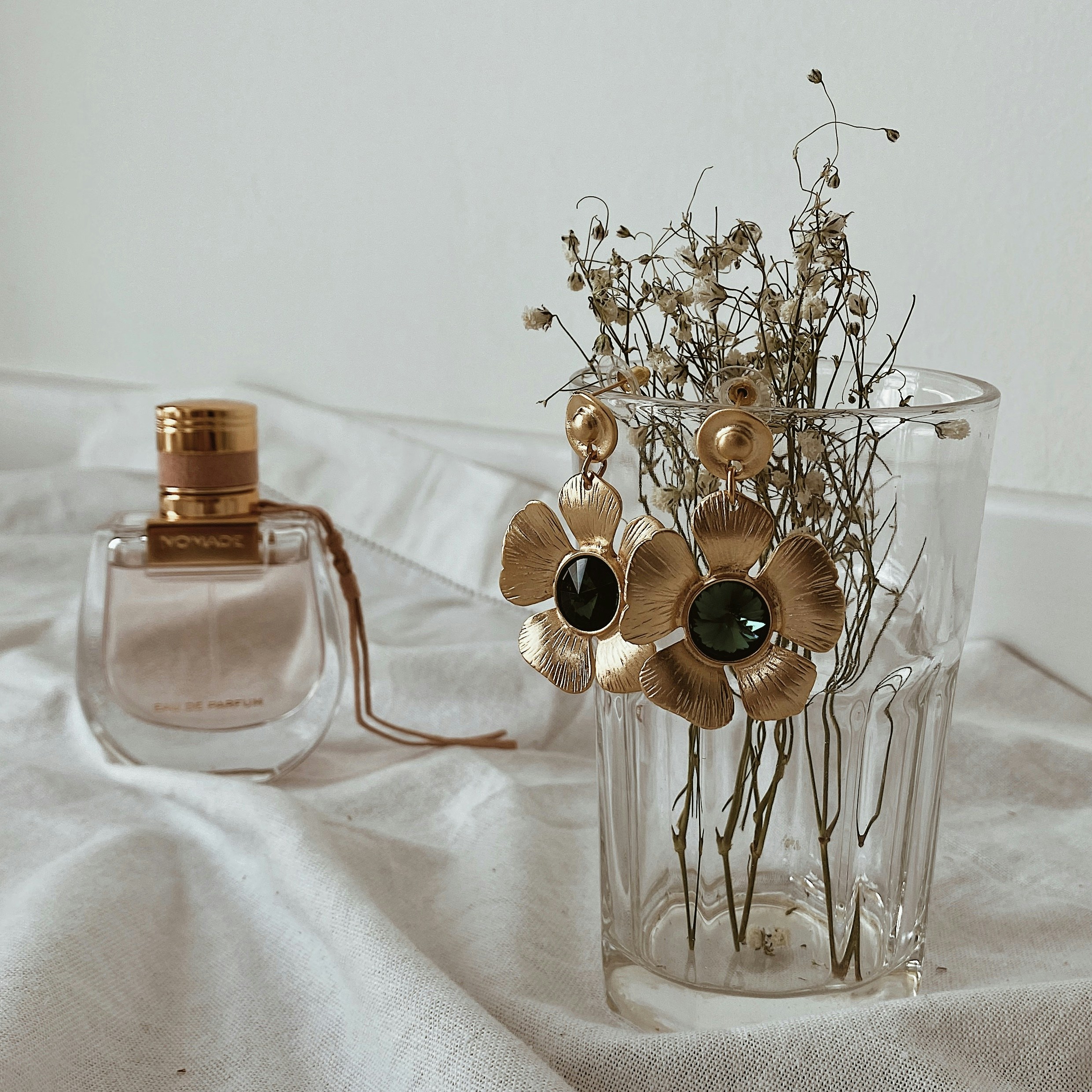 a vase filled with flowers next to a bottle of perfume