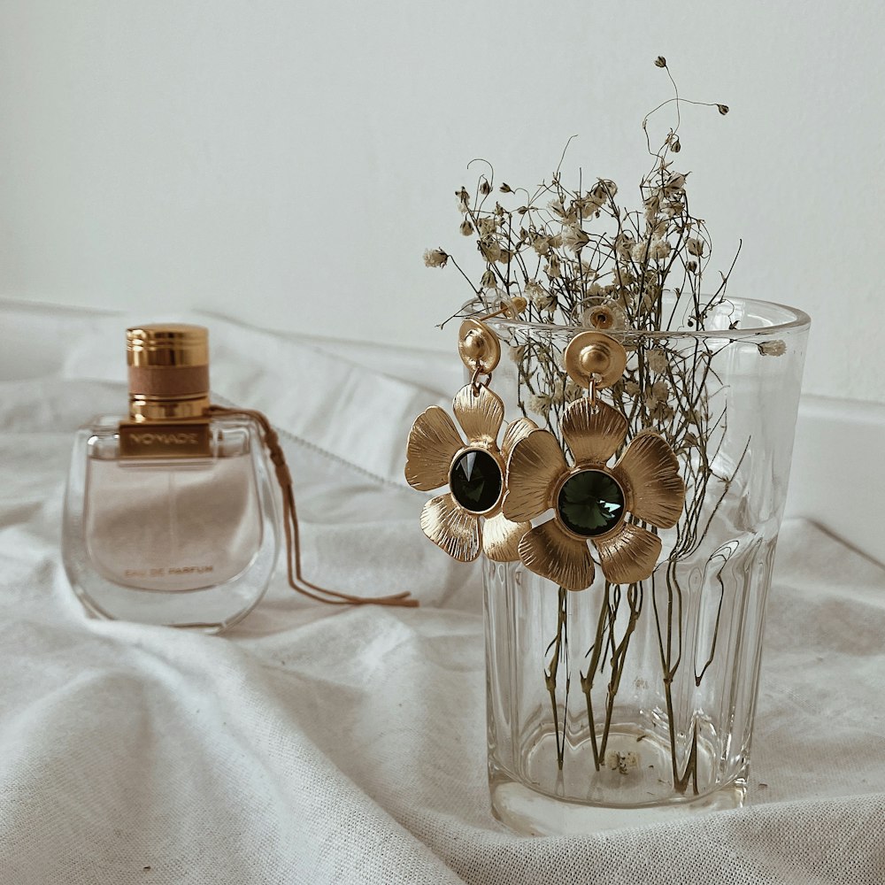 a vase filled with flowers next to a bottle of perfume