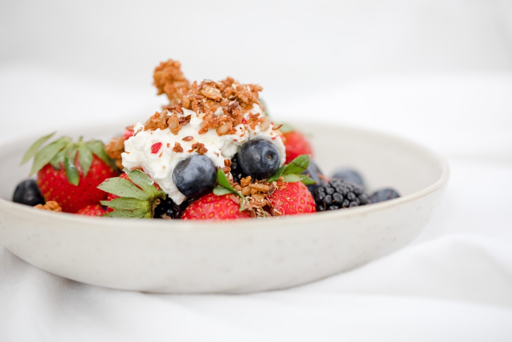 a white bowl filled with berries and granola