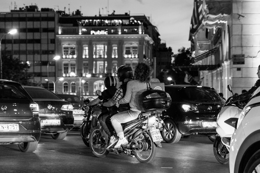 a black and white photo of two people on a motorcycle