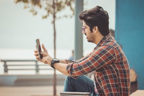 A person using a smartphone to access an online course while sitting in a park.