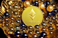 A shiny gold Ethereum coin is surrounded by an array of small, reflective spheres in various colors, including gold, blue, and black. The setup appears luxurious and depicts a sense of elegance and value.