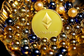 A shiny gold Ethereum coin is surrounded by an array of small, reflective spheres in various colors, including gold, blue, and black. The setup appears luxurious and depicts a sense of elegance and value.