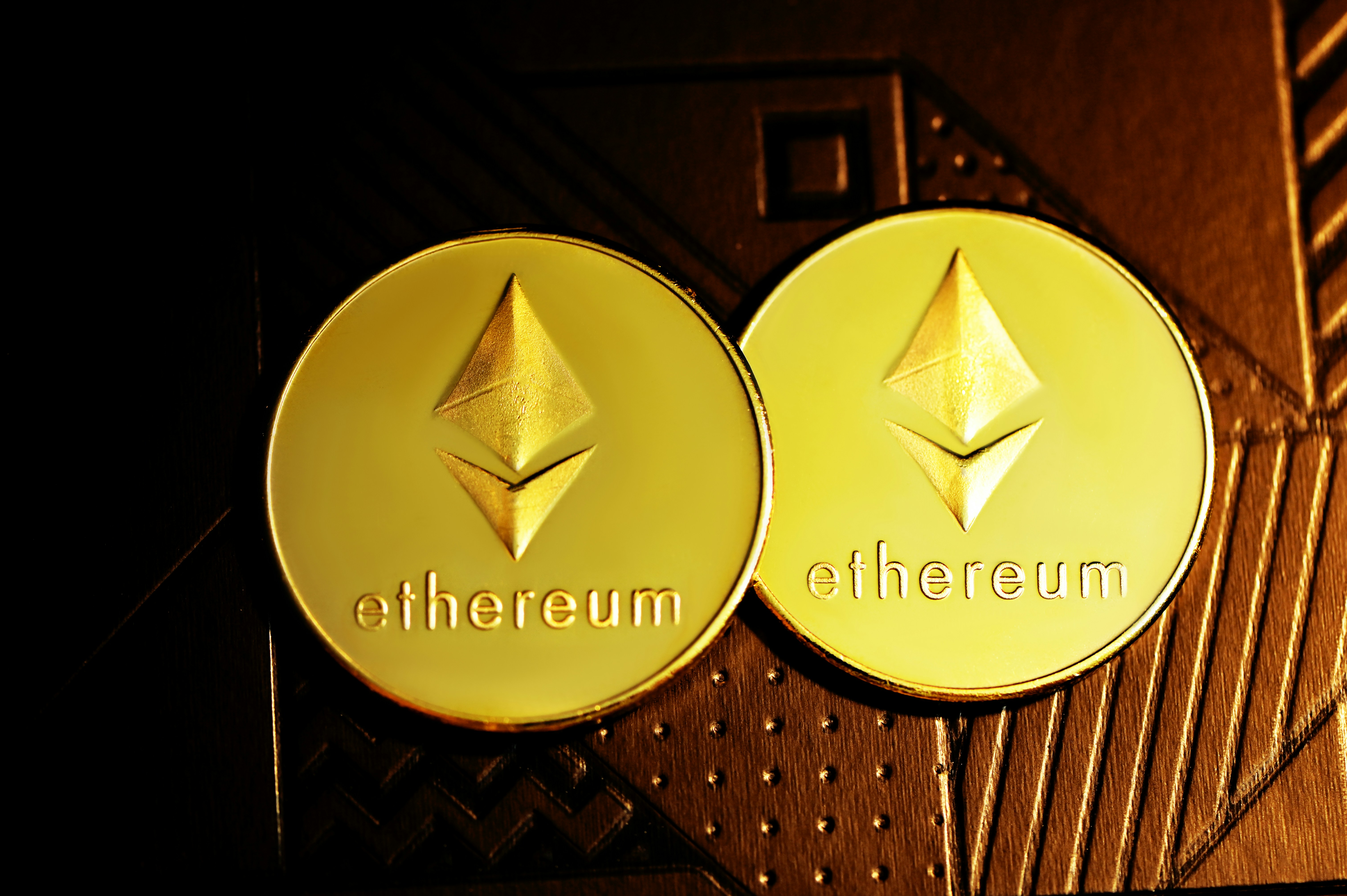Two Ethereum coins placed on a wood carving