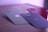 Four smartphone cases with camera cutouts are arranged on a flat surface. The cases are in various colors: green, beige, red, and black, each featuring a logo of a bitten apple. The lighting gives a soft purple hue to the scene.