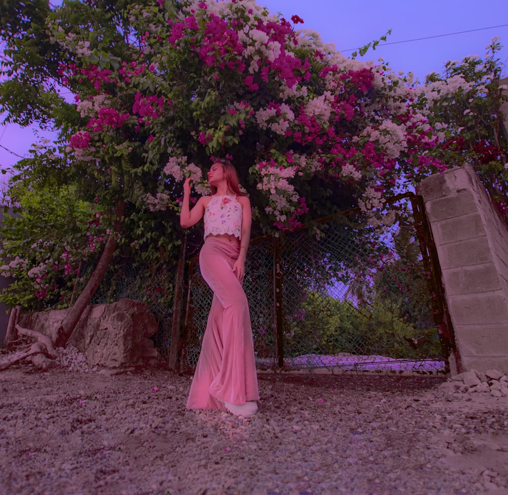 낮 동안 갈색 콘크리트 벽 근처에 서 있는 분홍색 드레스를 입은 여자